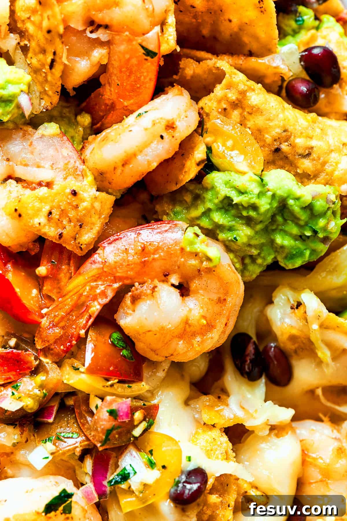 These crispy-crunchy Shrimp Nachos are piled with layers of flavor from creamy guacamole, juicy shrimp, and spicy, fresh pico de Gallo. Closes-up of shrimp nachos.