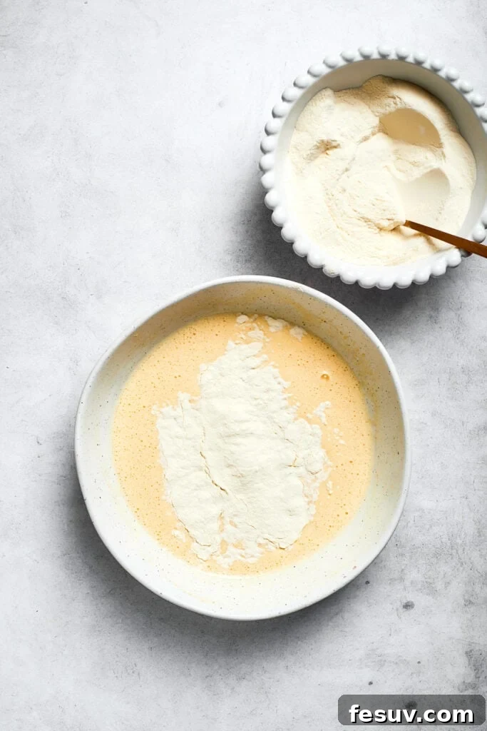 The whisked dry flour mixture is gently folded into the wet ingredients to create the cake batter, ensuring no lumps remain.