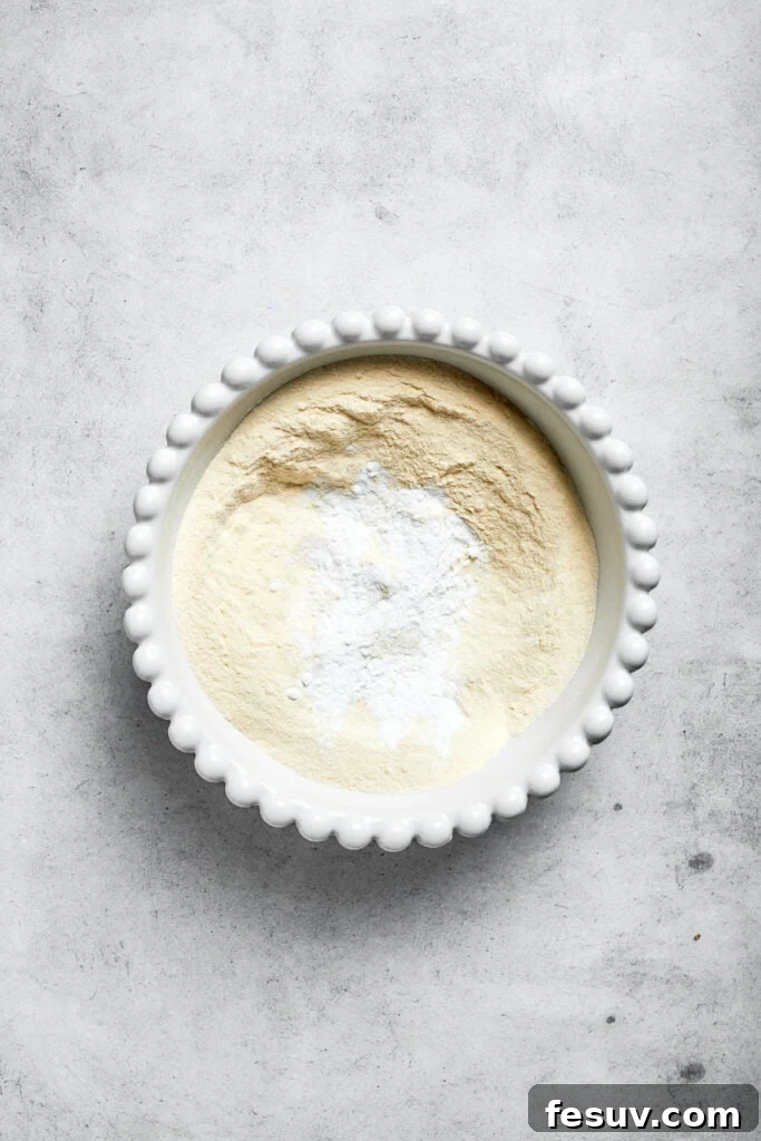 A bowl containing a mixture of dry cake ingredients: flour, baking powder, and salt, whisked together.