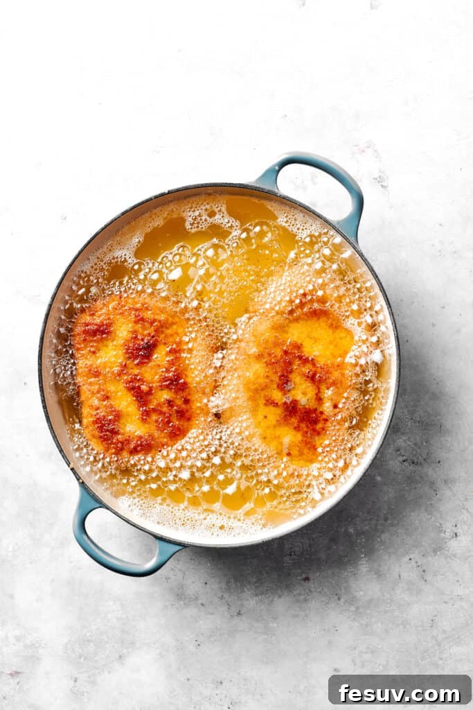 Pork cutlets frying to a golden crisp in hot oil.