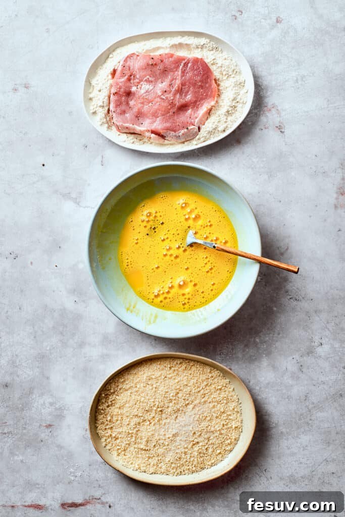 Breading station with separate bowls for flour, beaten egg, and panko breadcrumbs.