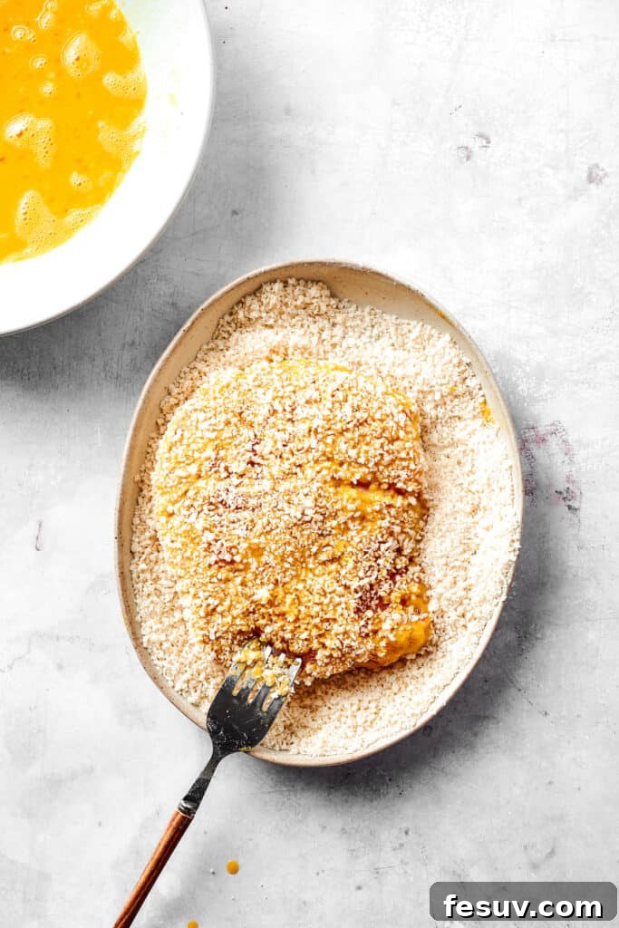 Pork cutlets being coated thoroughly with Panko breadcrumbs.