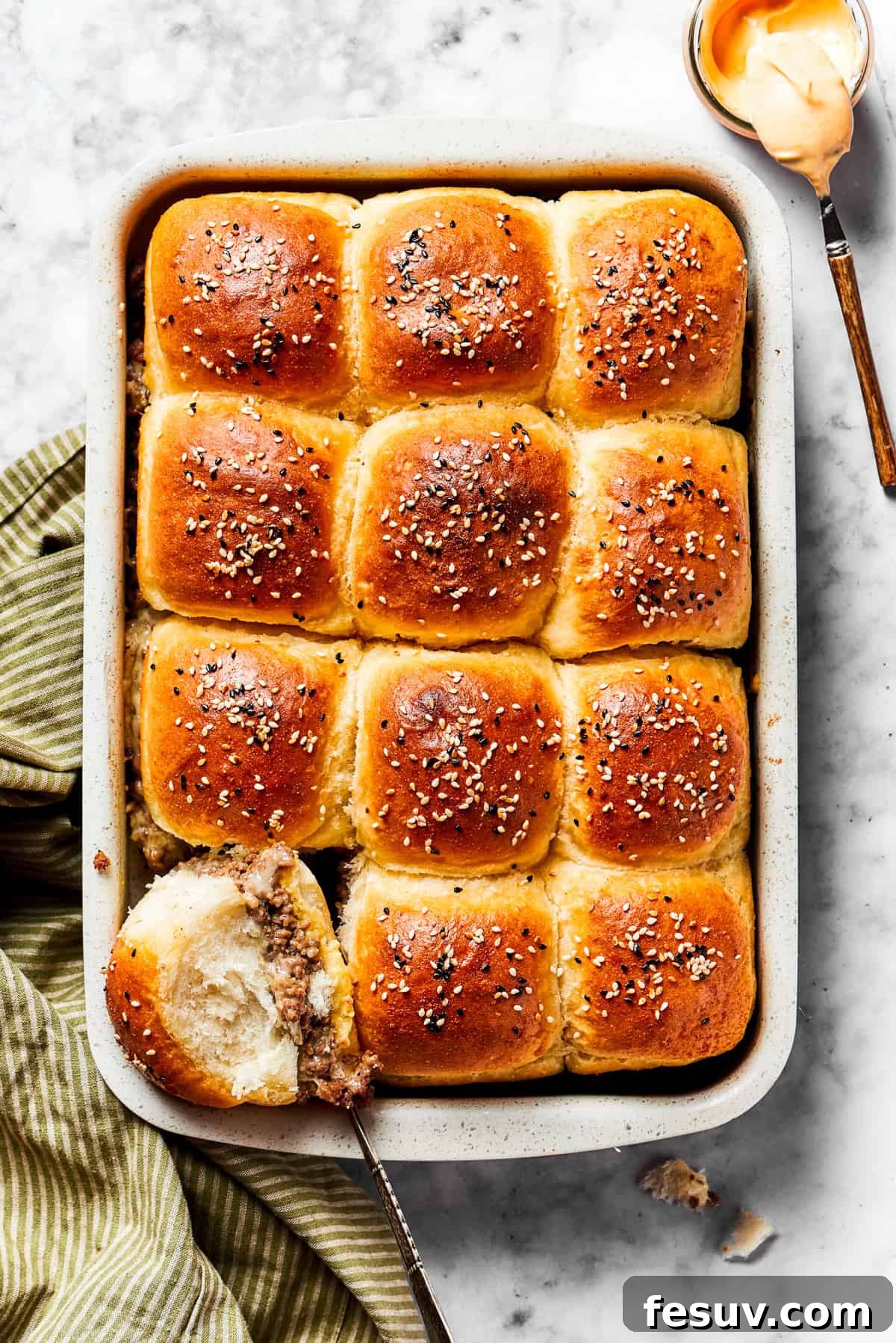 Cheeseburger sliders baked to perfection in a baking dish, with melted cheese oozing between the rolls.