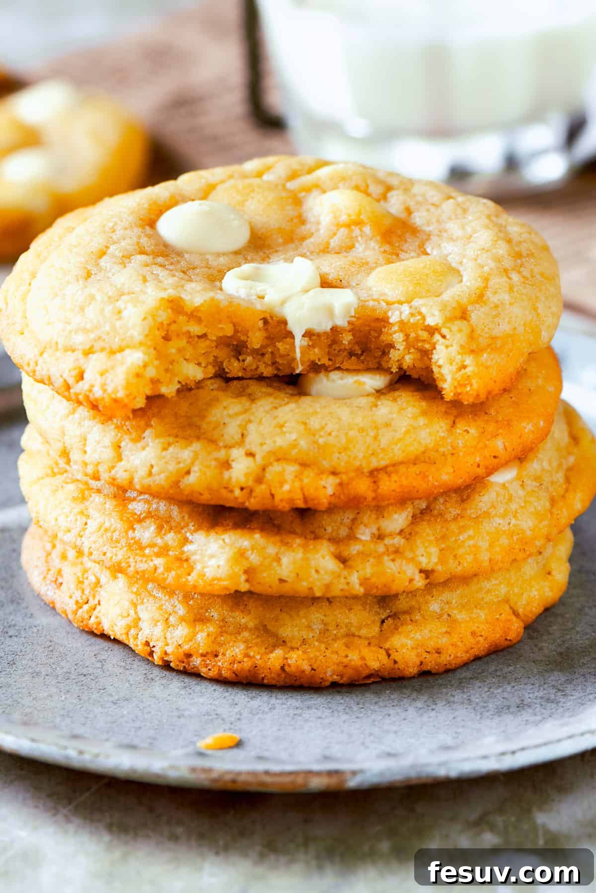 Chewy, buttery White Chocolate Chip Cookies are packed with creamy, sweet white chocolate chips instead of semisweet for an unexpected twist. Four perfectly baked white chocolate chip cookies are delicately stacked on a small, elegant white plate, their golden edges and creamy white chocolate chips visible, ready to be enjoyed.