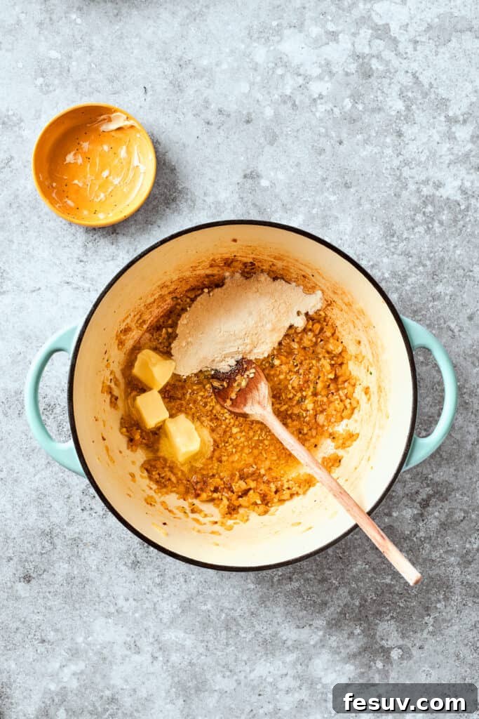 Butter and all-purpose flour are added to the skillet with sautéed garlic and onion, forming the base for a golden roux.