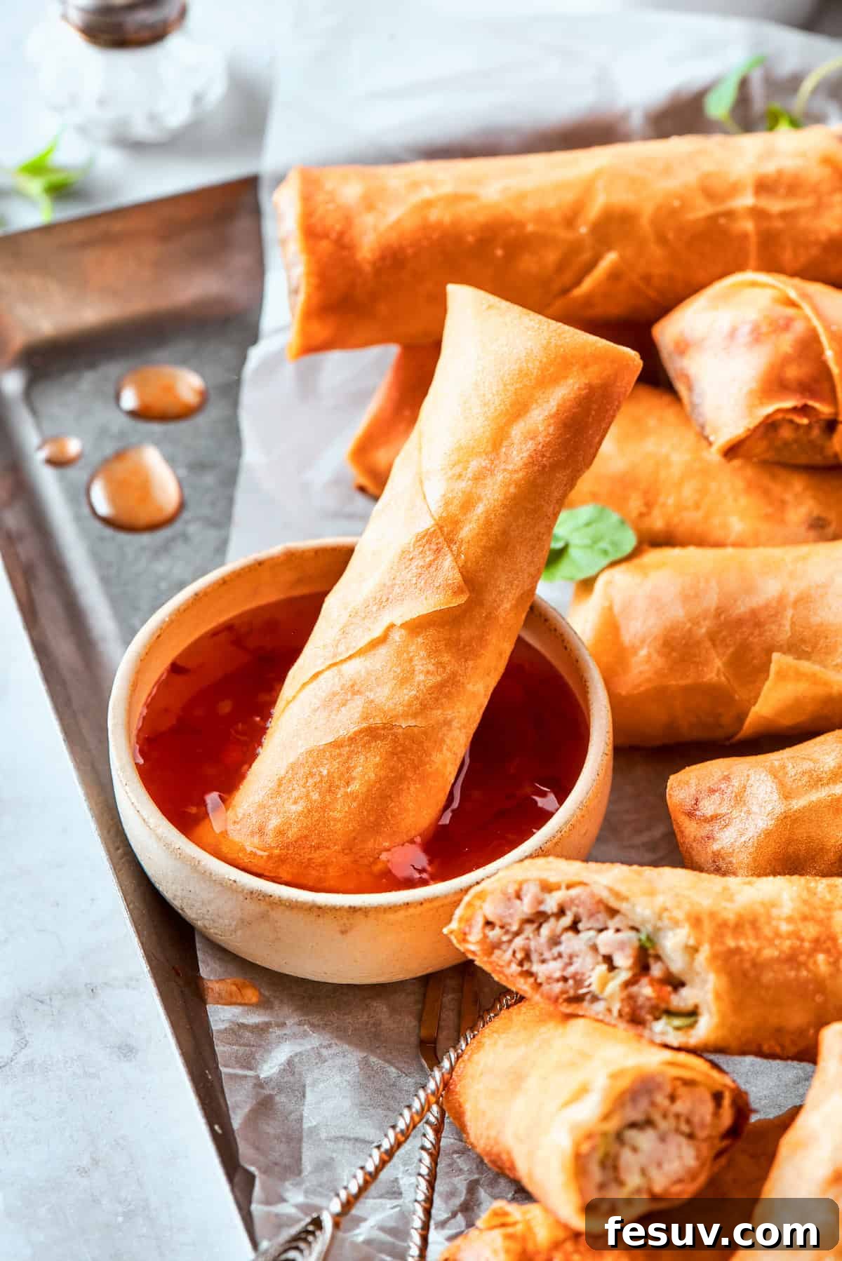 A vibrant close-up shot of several perfectly cooked chicken egg rolls, with one elegantly dipped into a rich, dark sauce, emphasizing their crispy texture and delicious appeal.