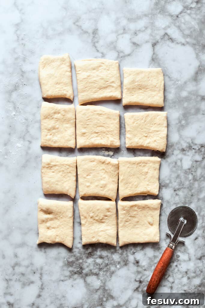 This easy Pizza Bites recipe stuffs spicy pepperoni and gooey mozzarella cheese into little pieces of pizza dough brushed with herb butter. The rolled-out pizza dough is precisely cut into 12 equal small squares using a sharp knife or pizza cutter.