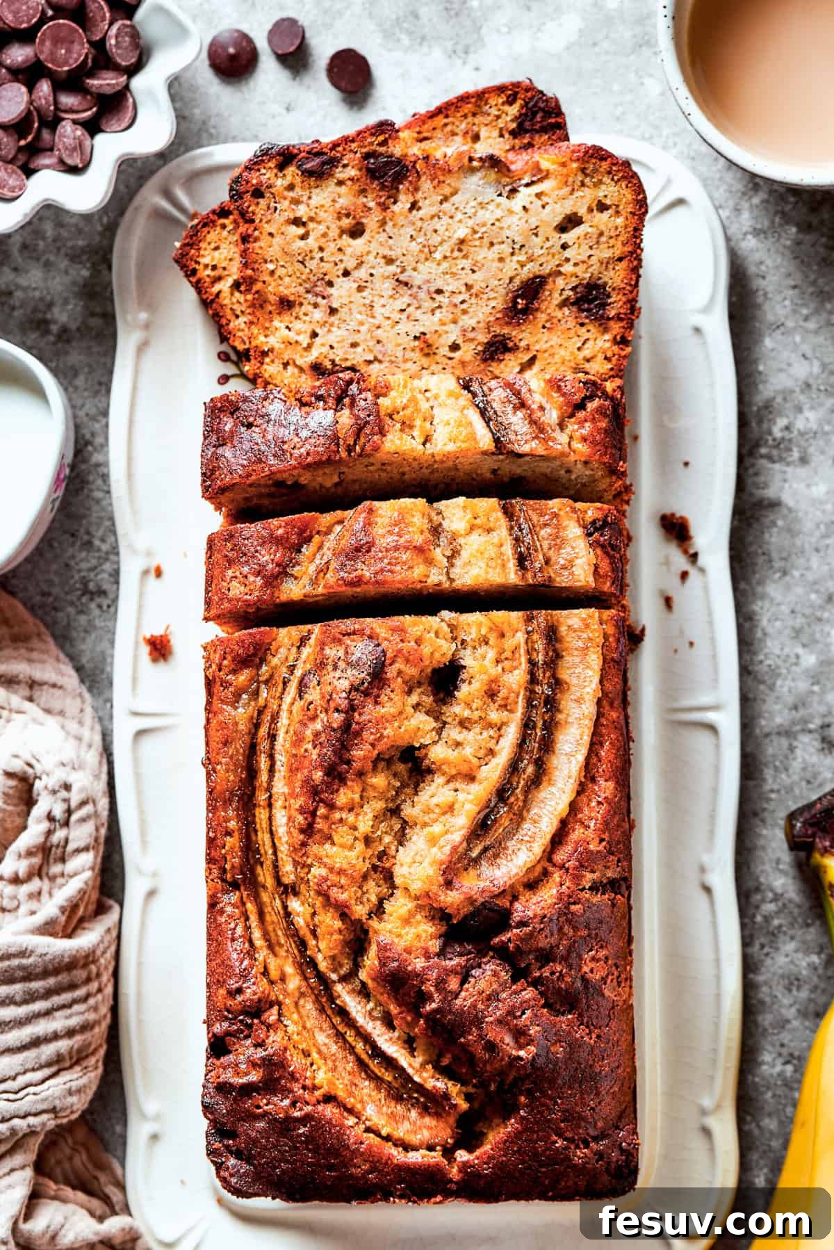 Deliciously moist sour cream banana bread studded with chocolate chips, presented in a loaf pan with ripe bananas and baking ingredients around it.