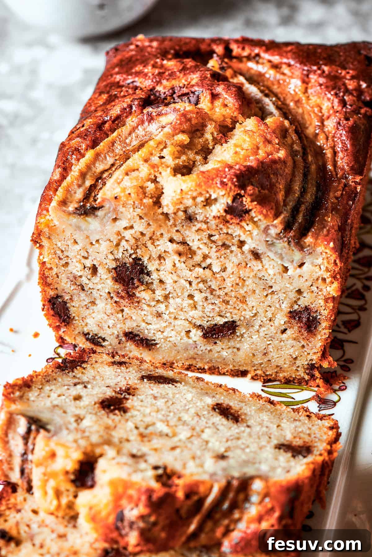 Close-up image of a freshly cut sour cream banana bread slice with the interior exposed to see its fluffy texture and generous chocolate chips.