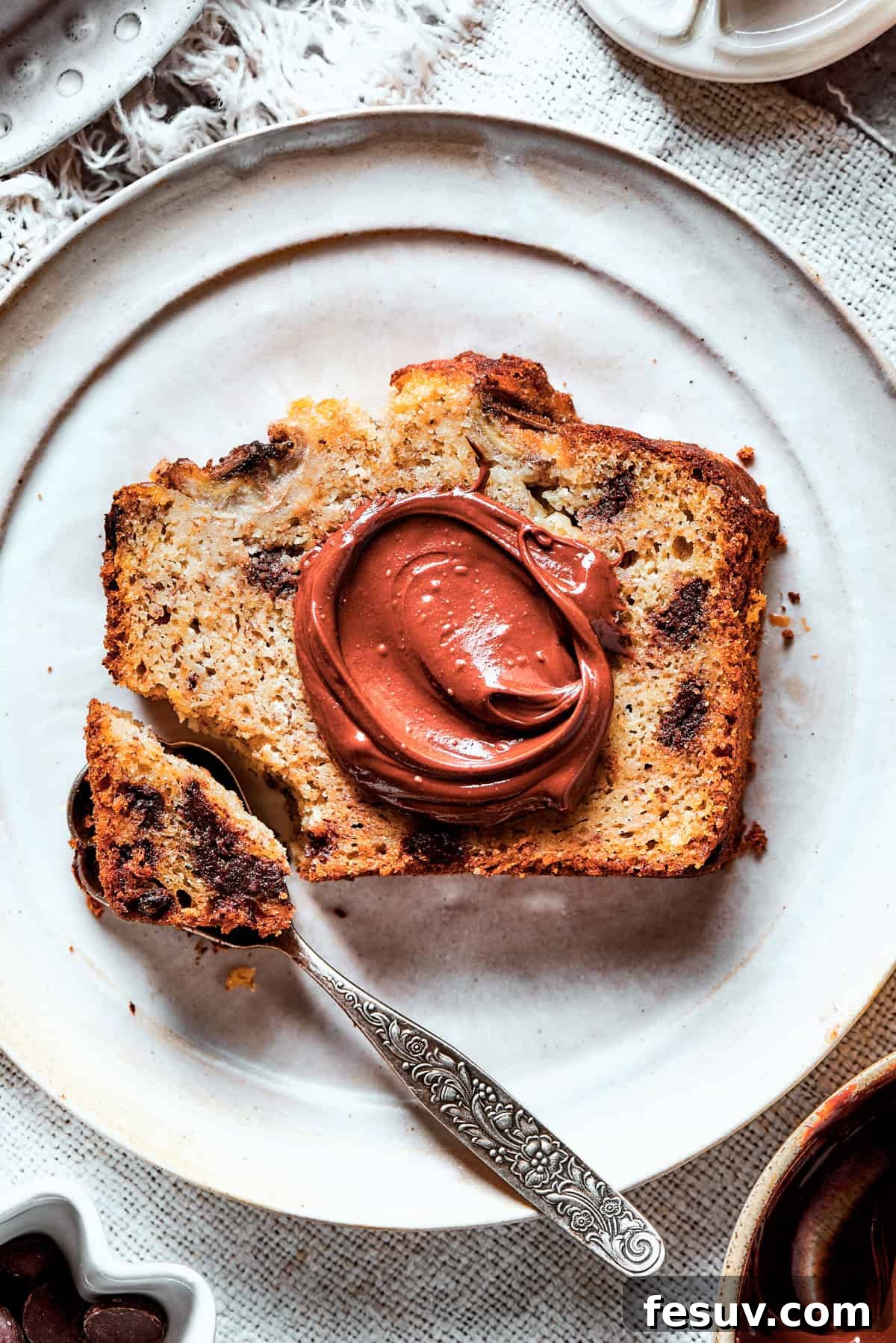 Spreading creamy Nutella generously over a slice of warm, moist banana bread.
