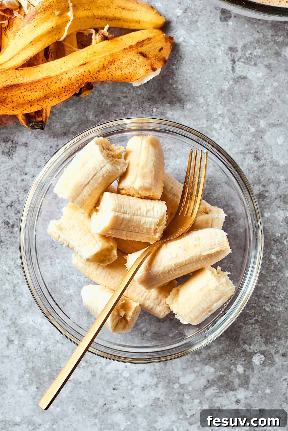 Mashed ripe bananas in a bowl with a fork, ready to be incorporated into the banana bread batter.