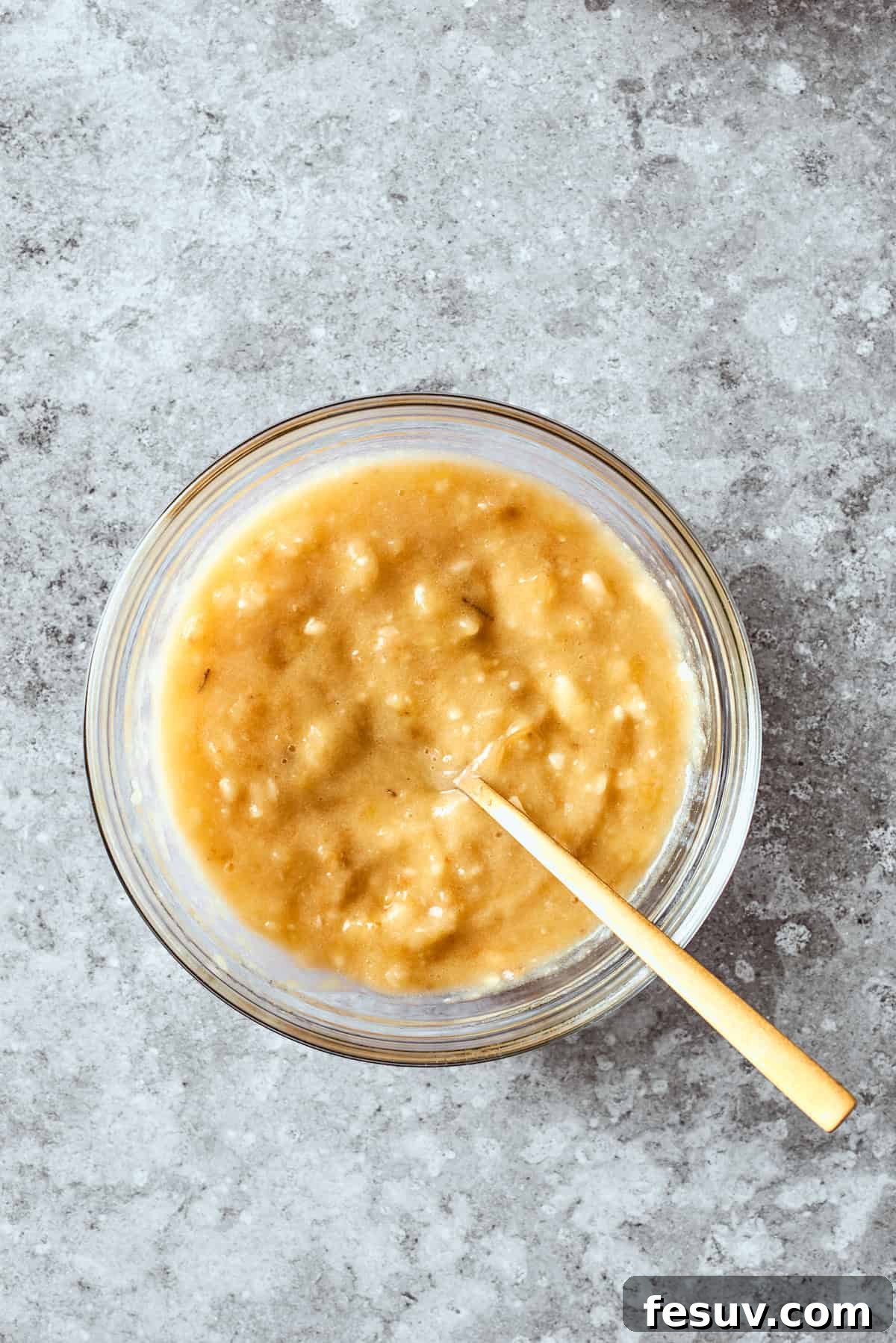 Adding mashed bananas to the wet mixture of eggs, sugar, butter, and sour cream.