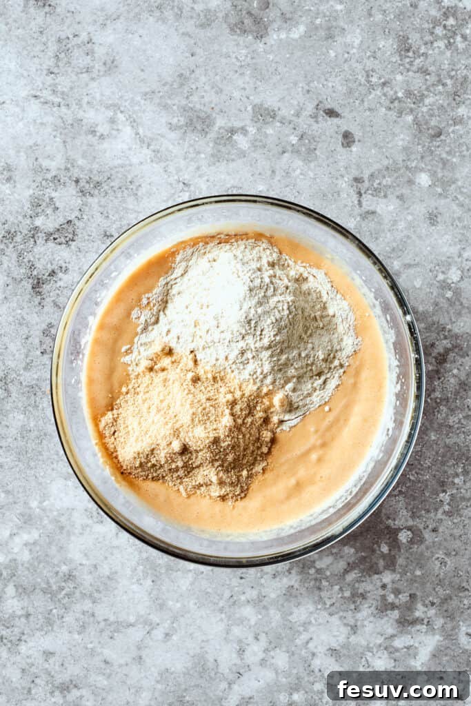 Dry ingredients, including all-purpose flour and almond flour, being gently added to the wet mixture.