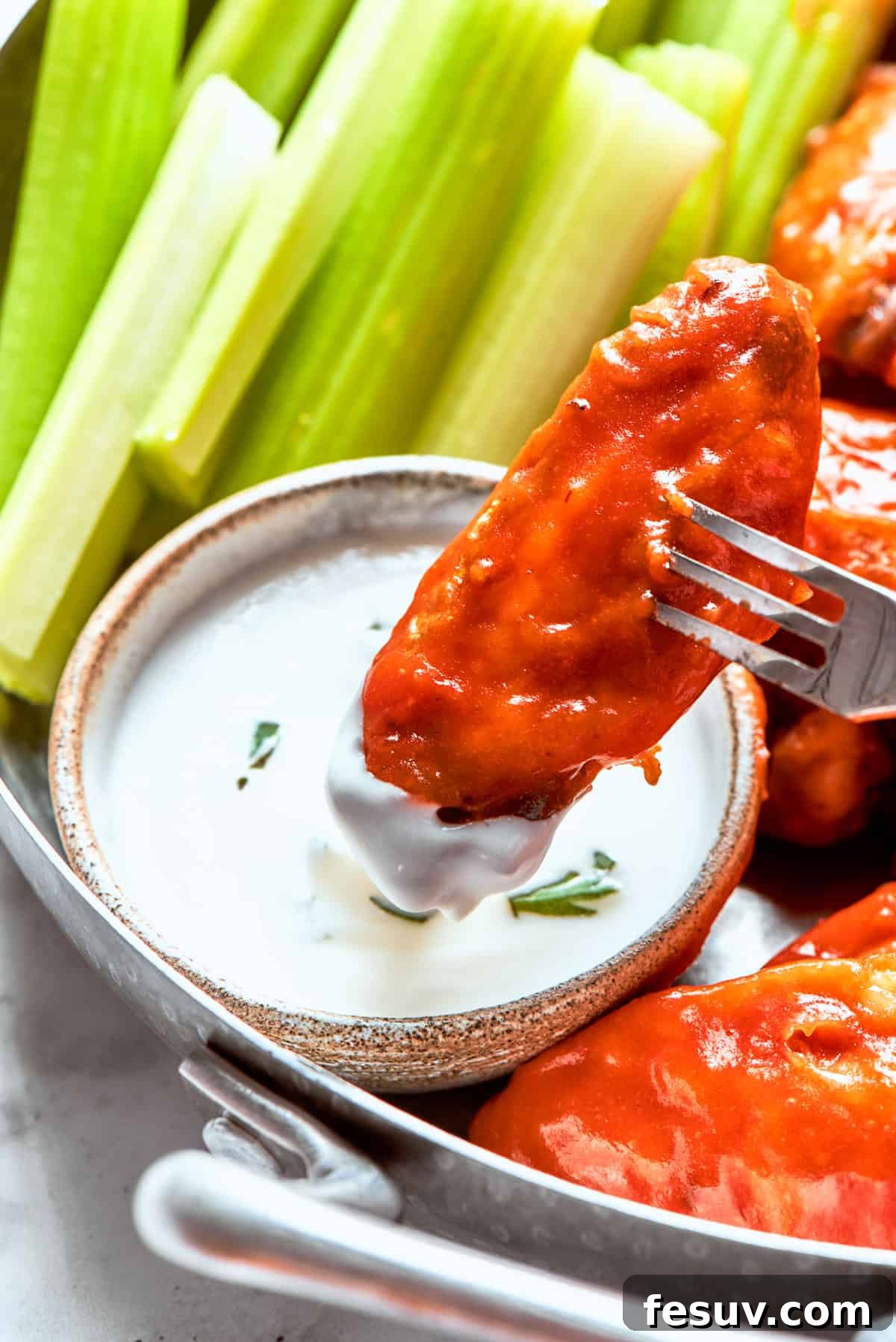 This easy Buffalo Wings recipe soaks crisp fried wings in a homemade buffalo sauce that's loaded with hot sauce and honey for intense flavor. Dipping a chicken wing into ranch sauce.