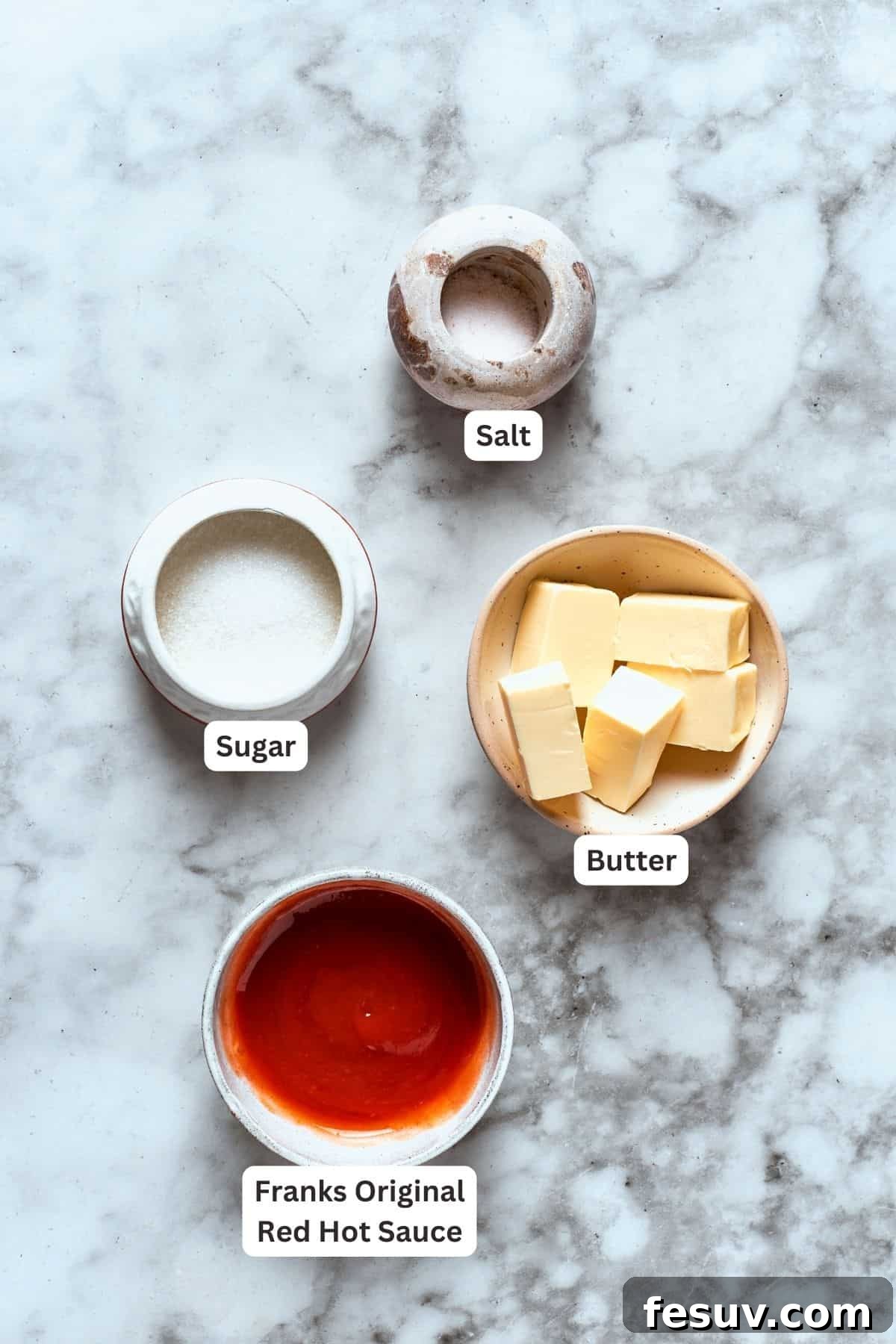 This easy Buffalo Wings recipe soaks crisp fried wings in a homemade buffalo sauce that's loaded with hot sauce and honey for intense flavor. Ingredients for buffalo wings sauce are labeled and portioned: butter, sugar, salt, hot sauce.
