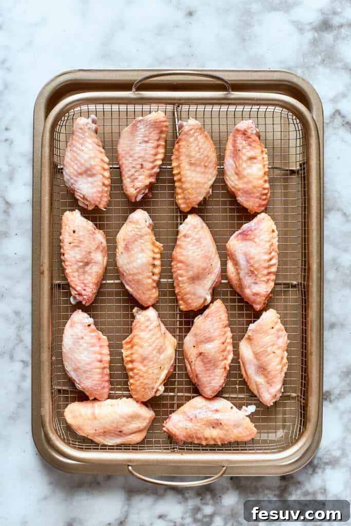 This easy Buffalo Wings recipe soaks crisp fried wings in a homemade buffalo sauce that's loaded with hot sauce and honey for intense flavor. The wings are shown on a baking tray.