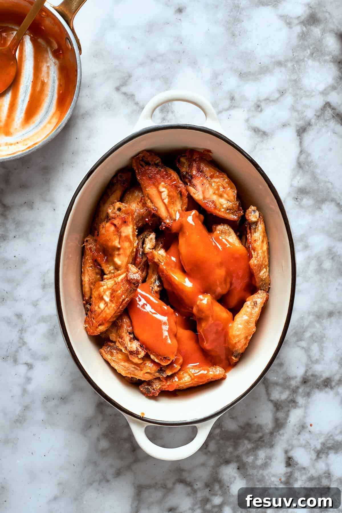 This easy Buffalo Wings recipe soaks crisp fried wings in a homemade buffalo sauce that's loaded with hot sauce and honey for intense flavor. The wings are topped with sauce.
