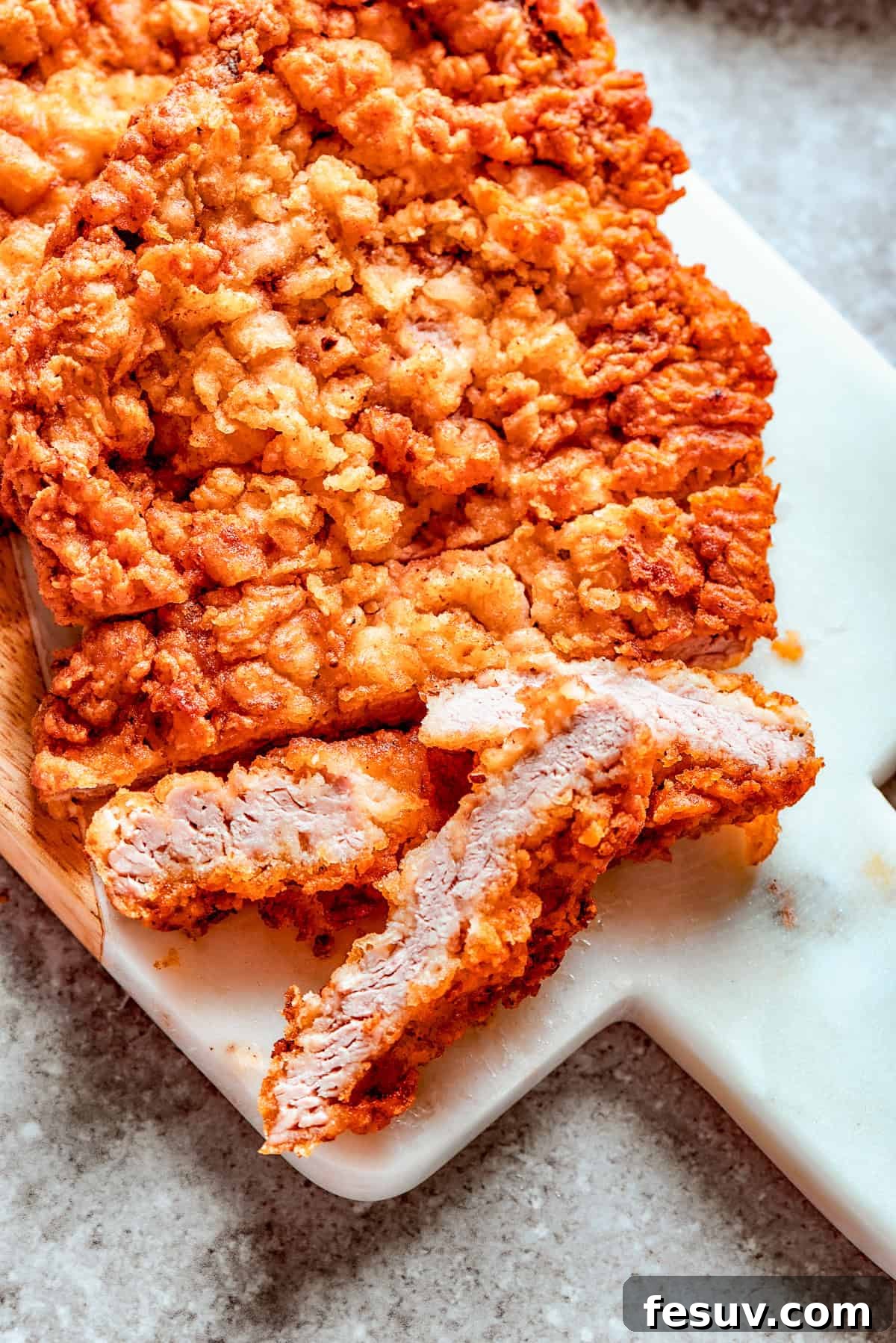 The perfect breading ready for frying to crispy perfection. A breaded chicken fried steak ready for frying on a cutting board.