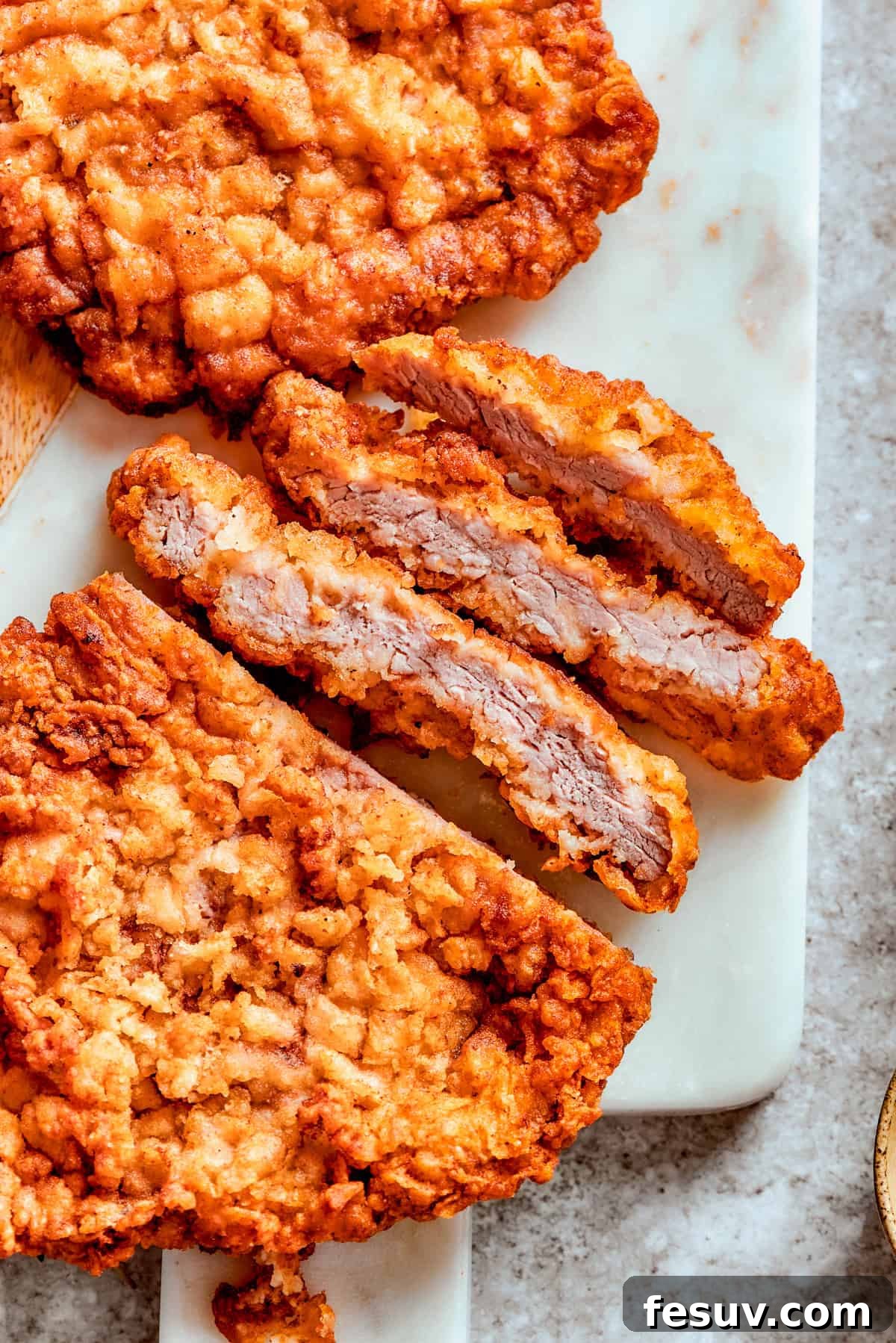 Enjoying a close-up of the delicious chicken fried steak. A perfectly fried, sliced chicken fried steak, revealing its tender interior.