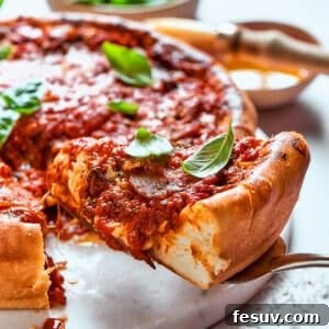 Serving spoon lifting out a slice of deep dish pizza.