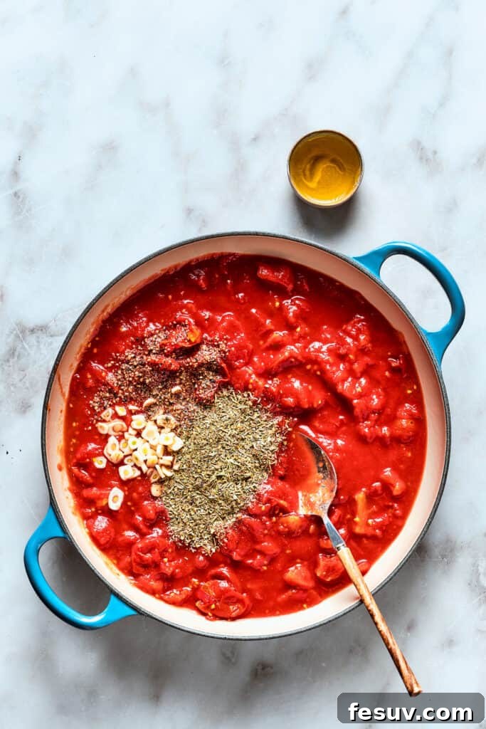 Prepare the flavorful tomato sauce for the deep dish pizza. A saucepan on a stovetop, simmering the thick, rich tomato sauce for deep dish pizza with various spices scattered on top, creating a flavorful aroma.