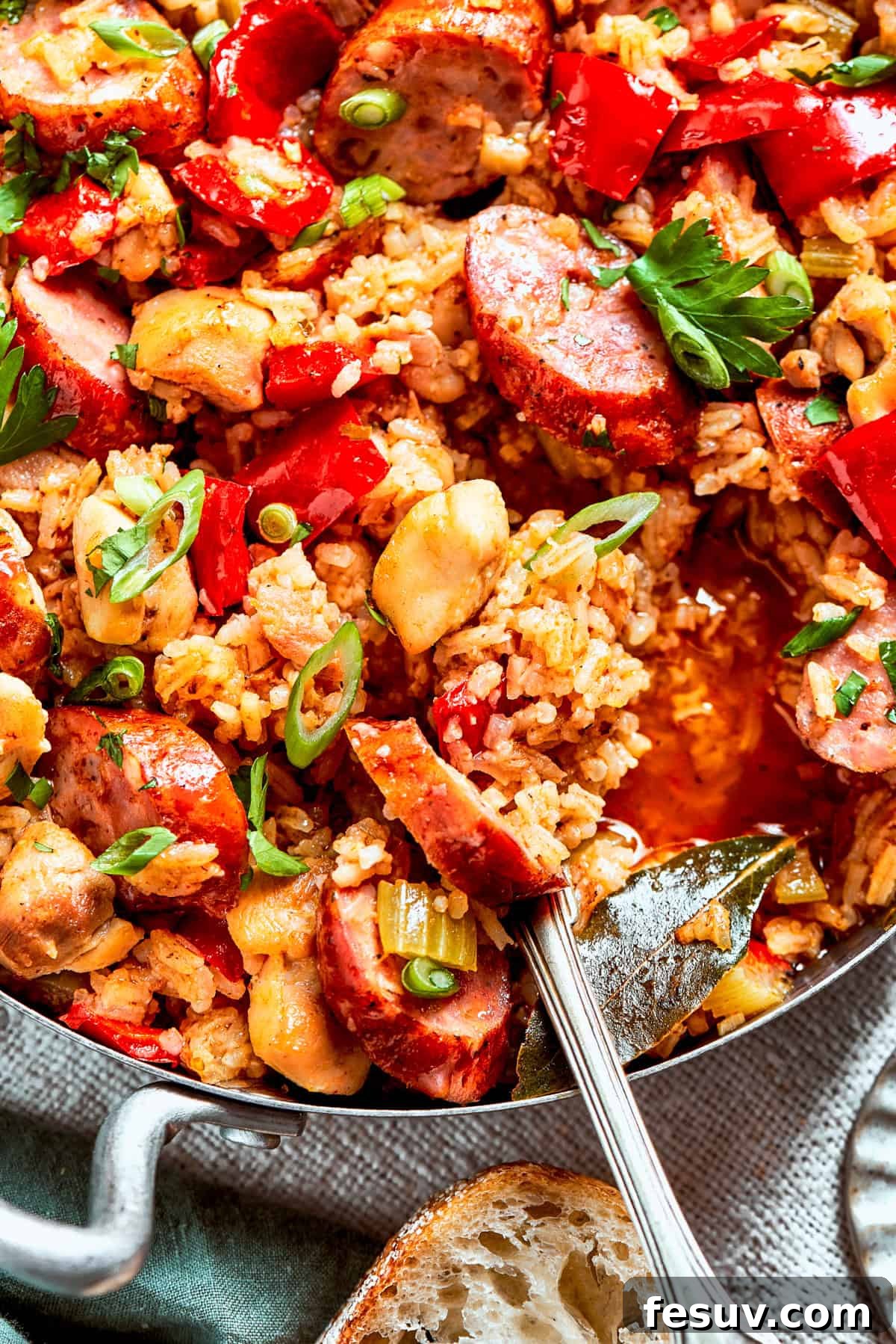 A pan of jambalaya with a serving spoon stirring through it.