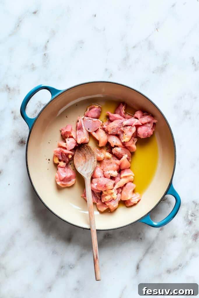 Chicken cooks in olive oil in a pot.