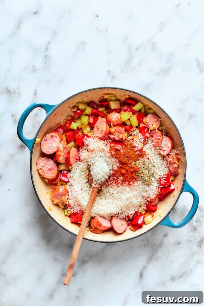 Spices and rice are added to the pot of jambalaya.