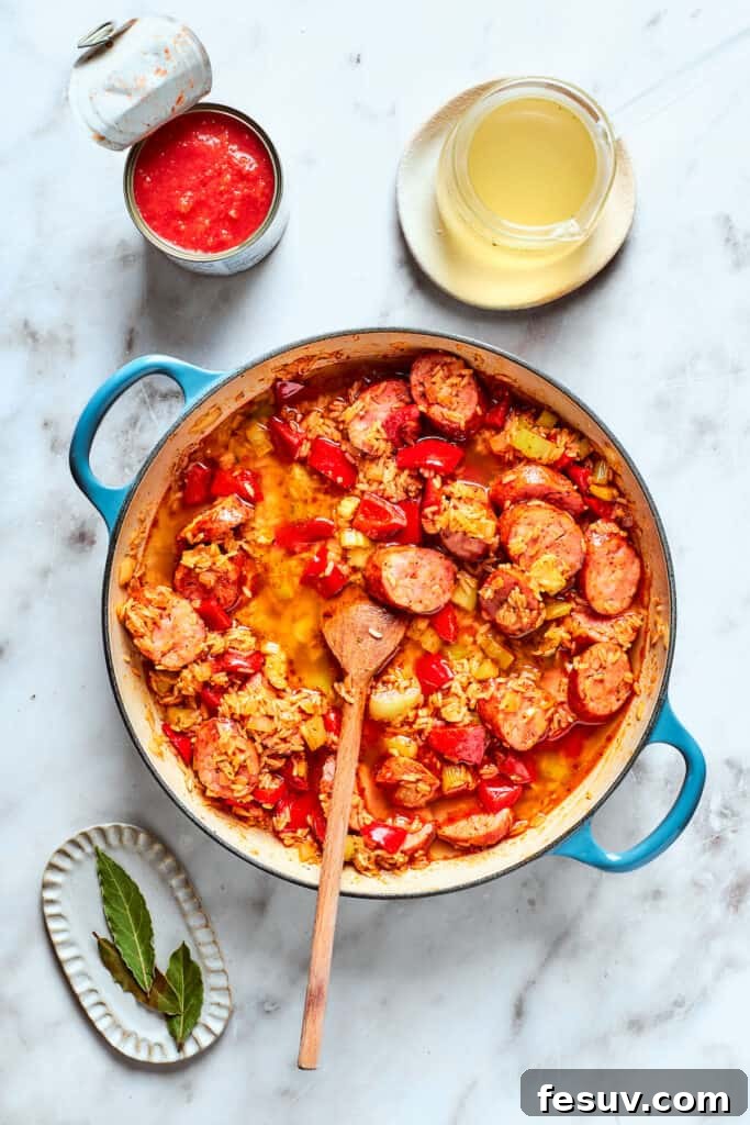 A wooden spoon stirs the jambalaya together.