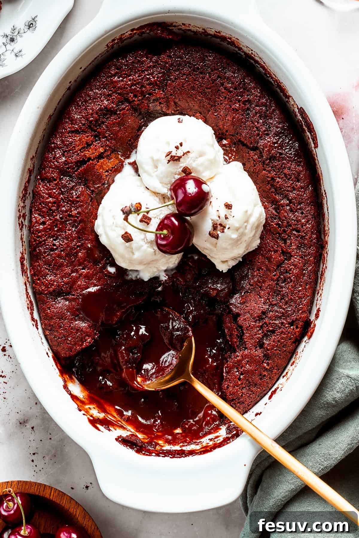 Heavenly Chocolate Pudding Cake 2 An oval casserole dish with chocolate pudding cake topped with vanilla ice cream, with a spoon set in the pudding.