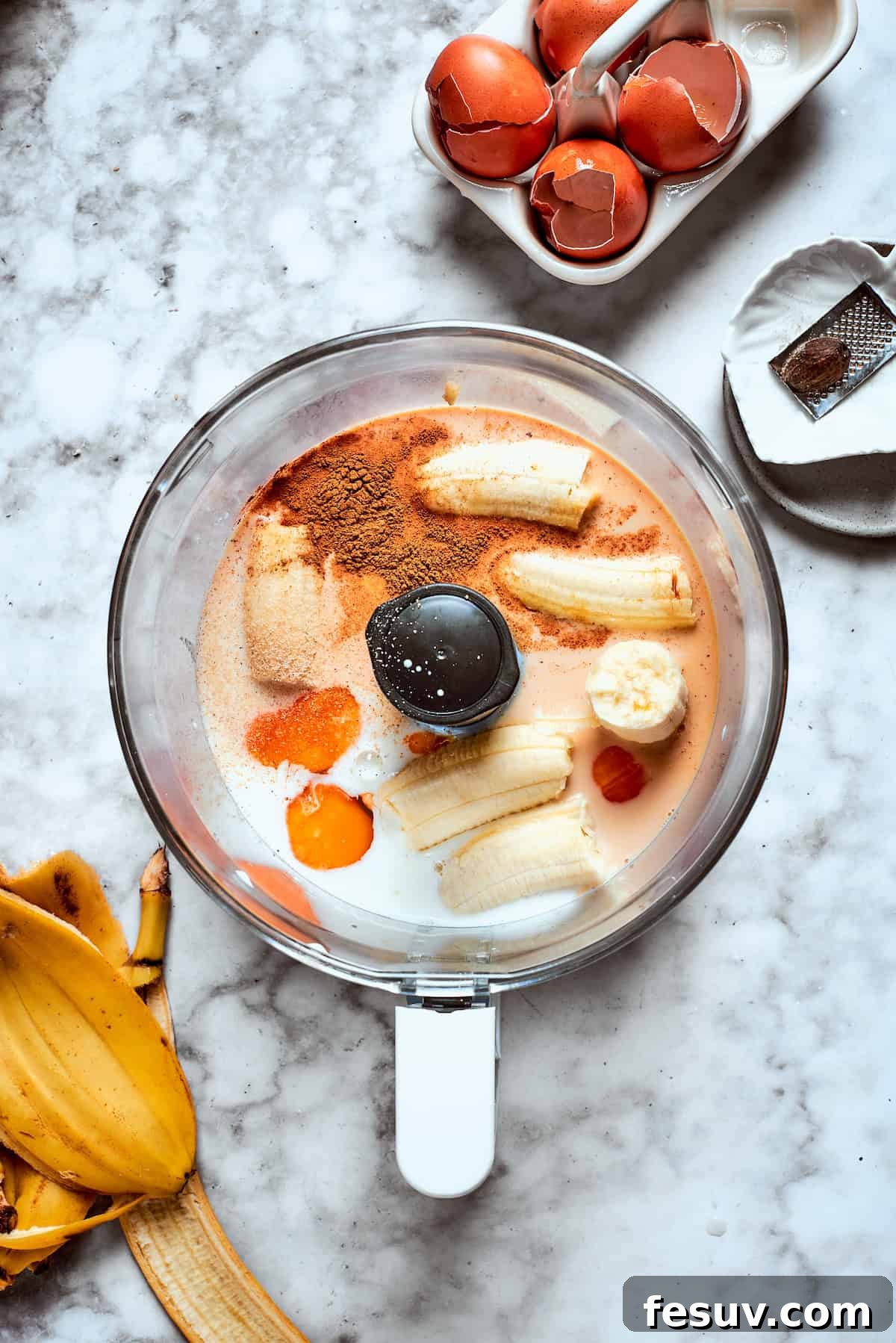 Assembling batter ingredients in a food processor. Ripe bananas and all the other liquid batter ingredients are carefully placed into the bowl of a food processor, ready for blending.