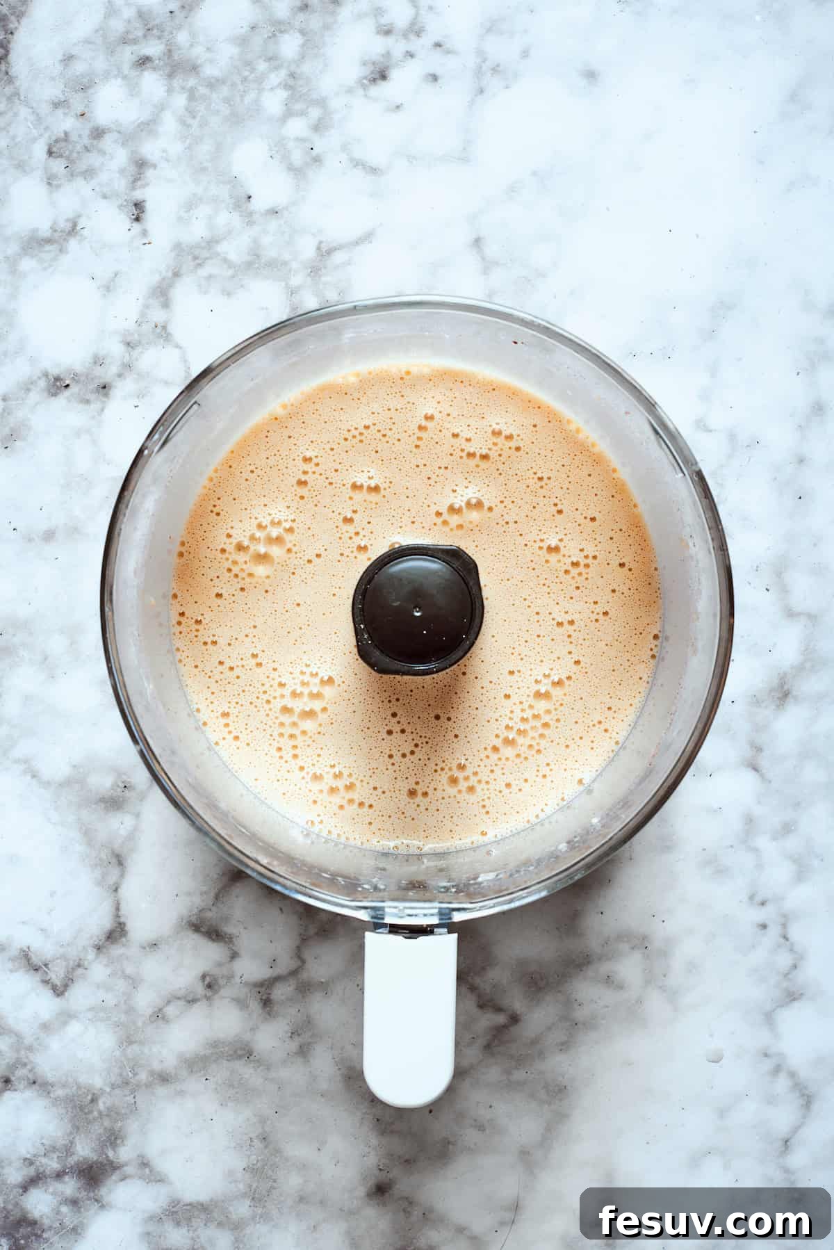 Blending the banana batter until smooth. The banana French toast batter is being pureed in a food processor until it reaches a perfectly smooth and creamy consistency, free of any lumps.