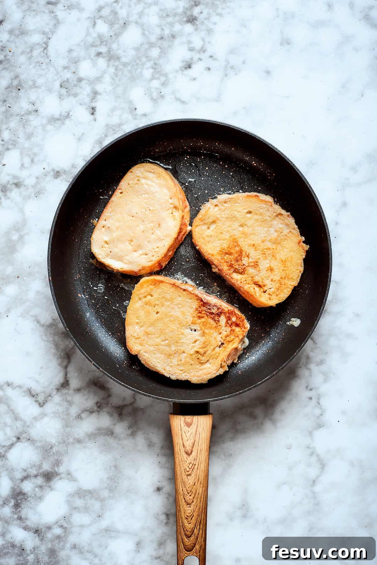 Frying French toast in a skillet until golden. Several pieces of banana French toast are sizzling and browning beautifully in a skillet, creating a delicious golden crust.