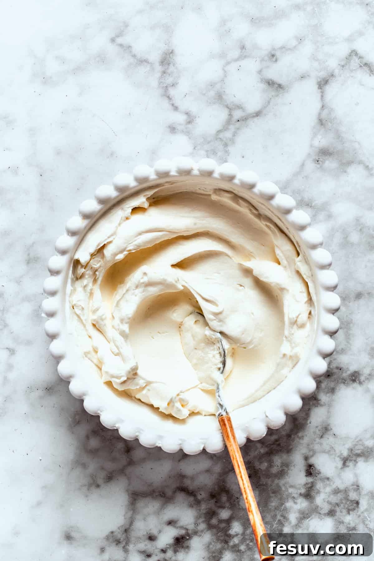 This easy Sex in a Pan recipe layers a tangy-sweet cream cheese filling with vanilla and chocolate puddings on top of a pecan crust. The cream cheese layer is mixed in a bowl until smooth.