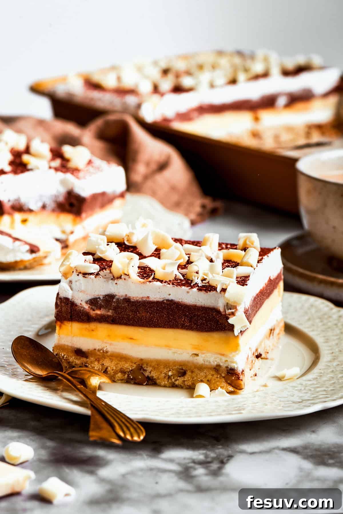 This easy Sex in a Pan recipe layers a tangy-sweet cream cheese filling with vanilla and chocolate puddings on top of a pecan crust. A finished Sex in a Pan dessert, ready to be cut and served.