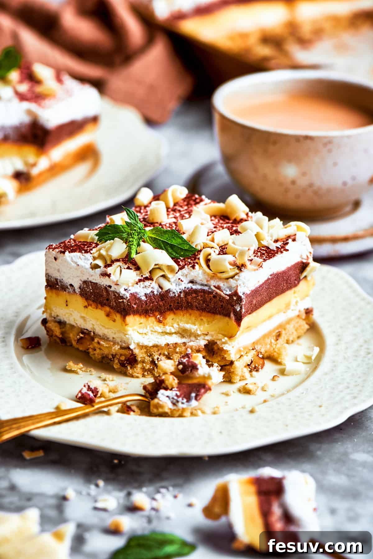 This easy Sex in a Pan recipe layers a tangy-sweet cream cheese filling with vanilla and chocolate puddings on top of a pecan crust. A layered no-bake dessert called sex in a pan served on a plate with elegant chocolate curls.