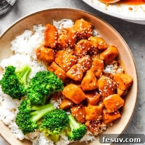 Teriyaki chicken pieces served over rice in a bowl with a side of broccoli.