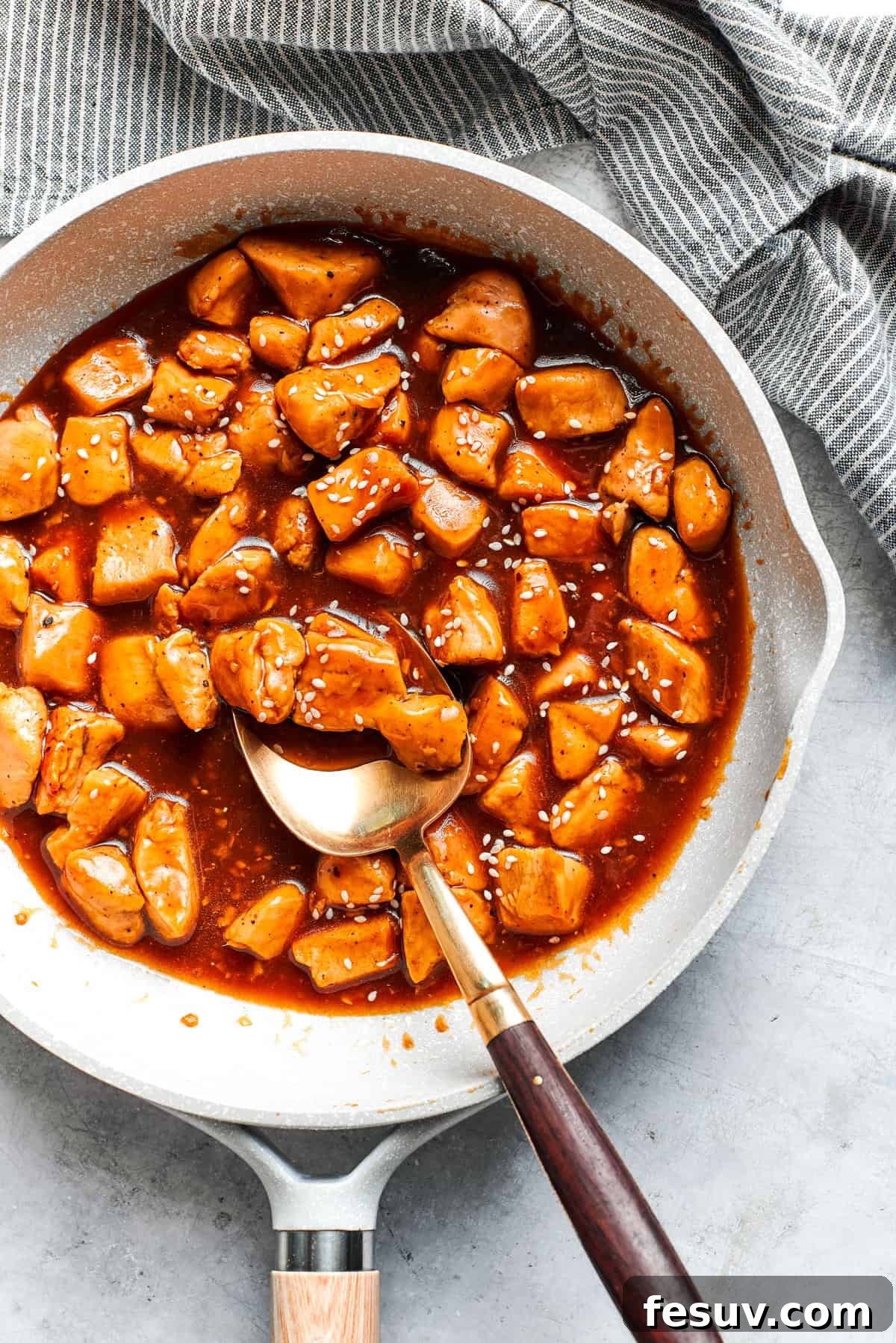 Cubes of chicken cooking in a sauce.
