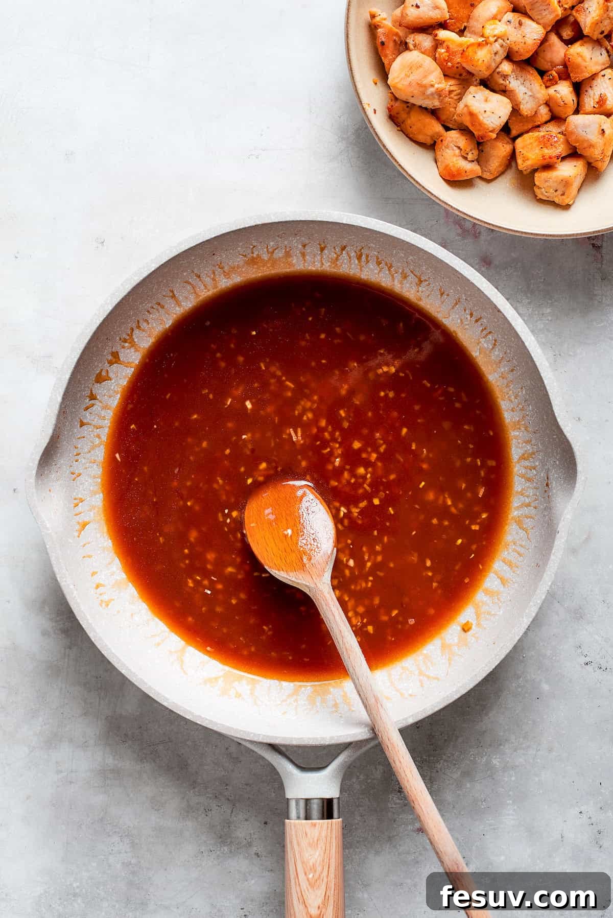A spoon combines the teriyaki sauce in a pan.