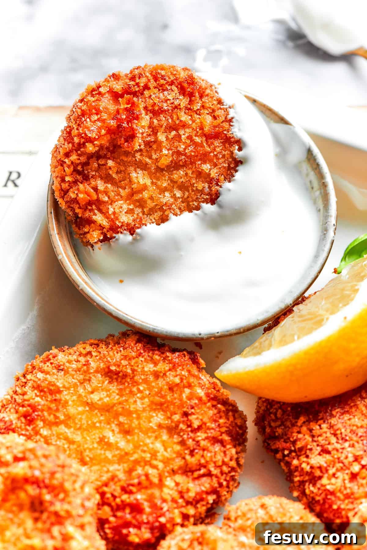 A chicken nugget in a dish of Ranch dip.