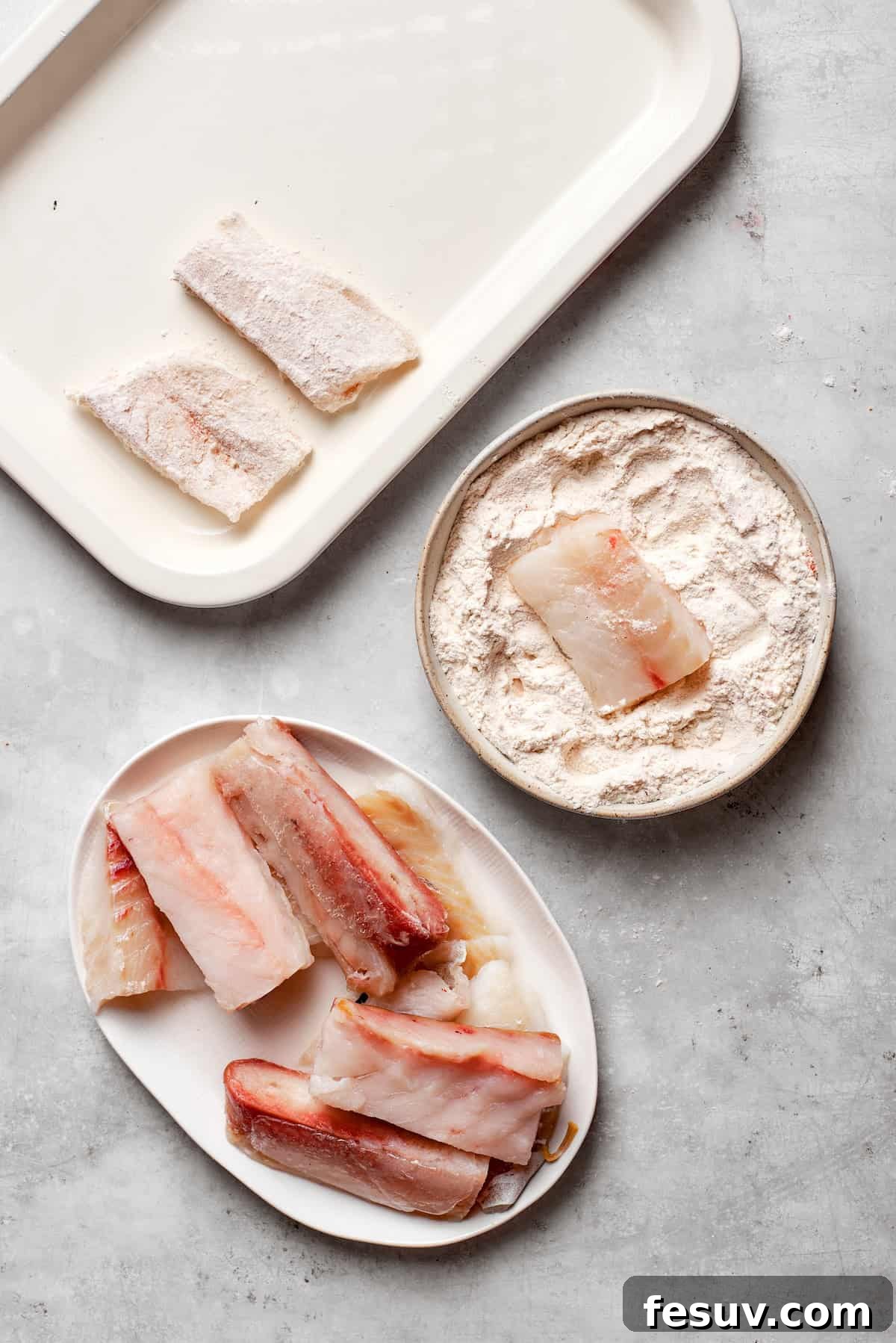 A piece of white fish is being dredged in a shallow dish of seasoned flour.