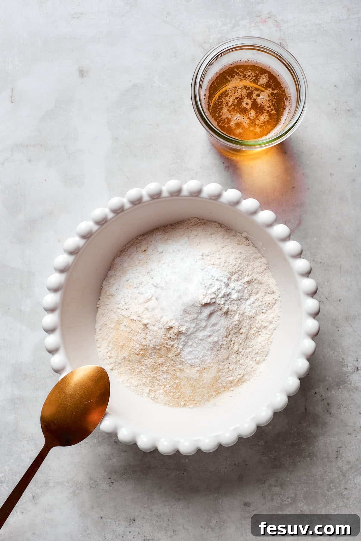 Dry ingredients for the beer batter, including flour, salt, baking powder, and garlic powder, are added to a mixing bowl.