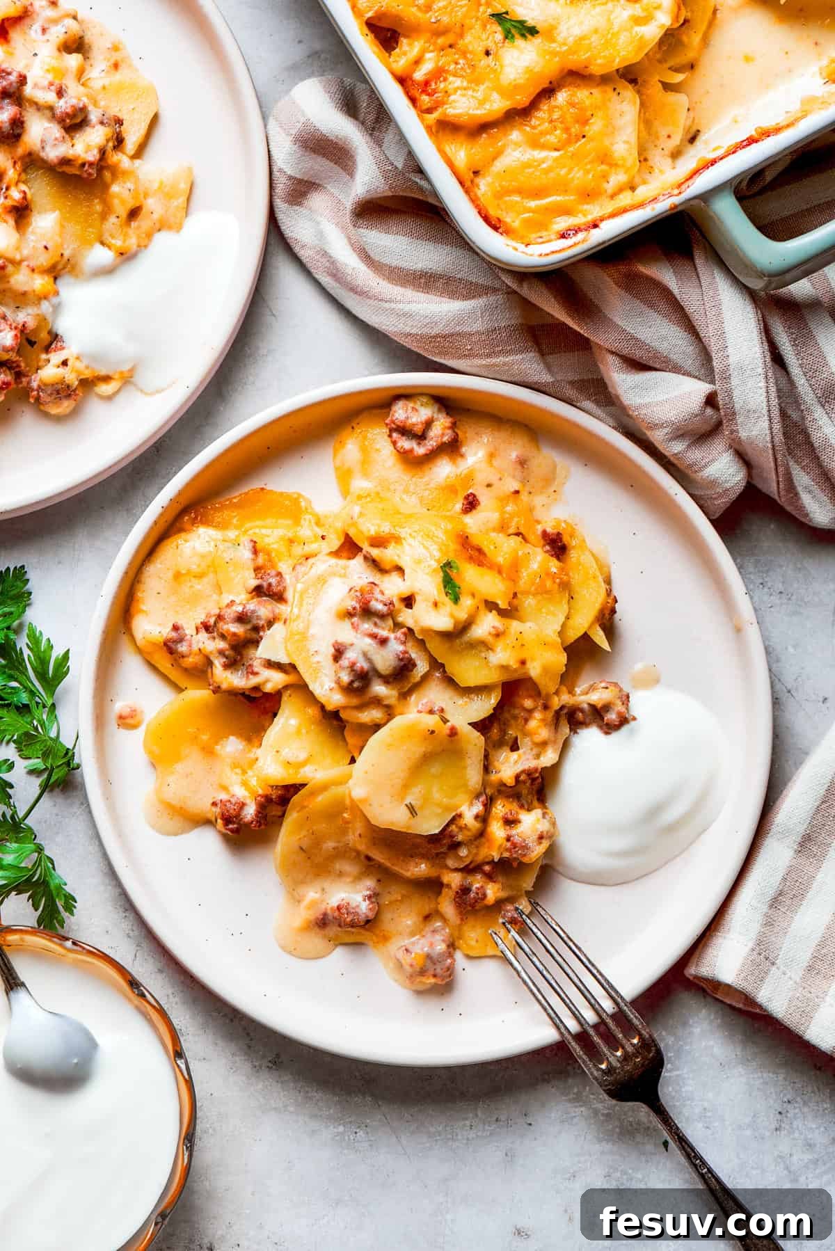 Served portions of Hamburger Potato Casserole on dinner plates. A generous portion of creamy Hamburger Potato Casserole, topped with melted golden cheese, is served on elegant dinner plates, inviting guests to enjoy.