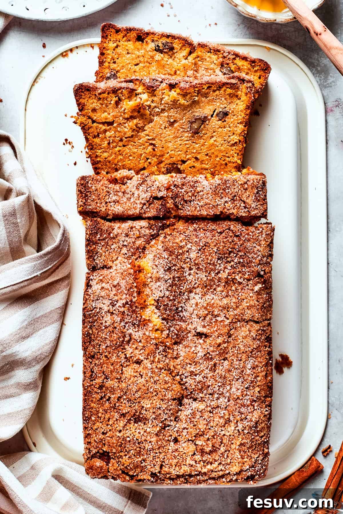 A loaf of Amish friendship bread is sliced on a cutting board, showcasing its cinnamon swirl.