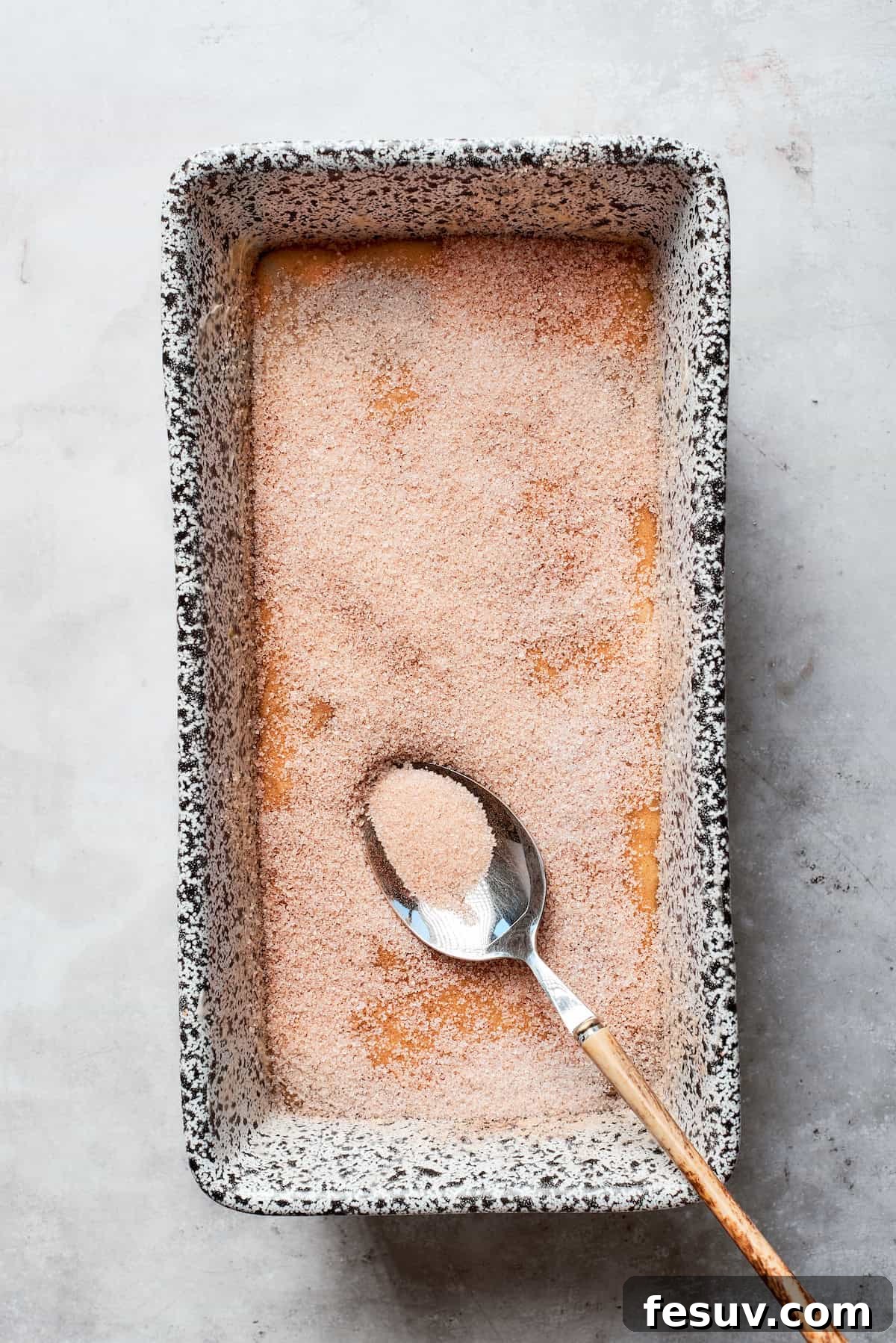 The cinnamon sugar mixture is evenly sprinkled over the top of the batter in the loaf pan.