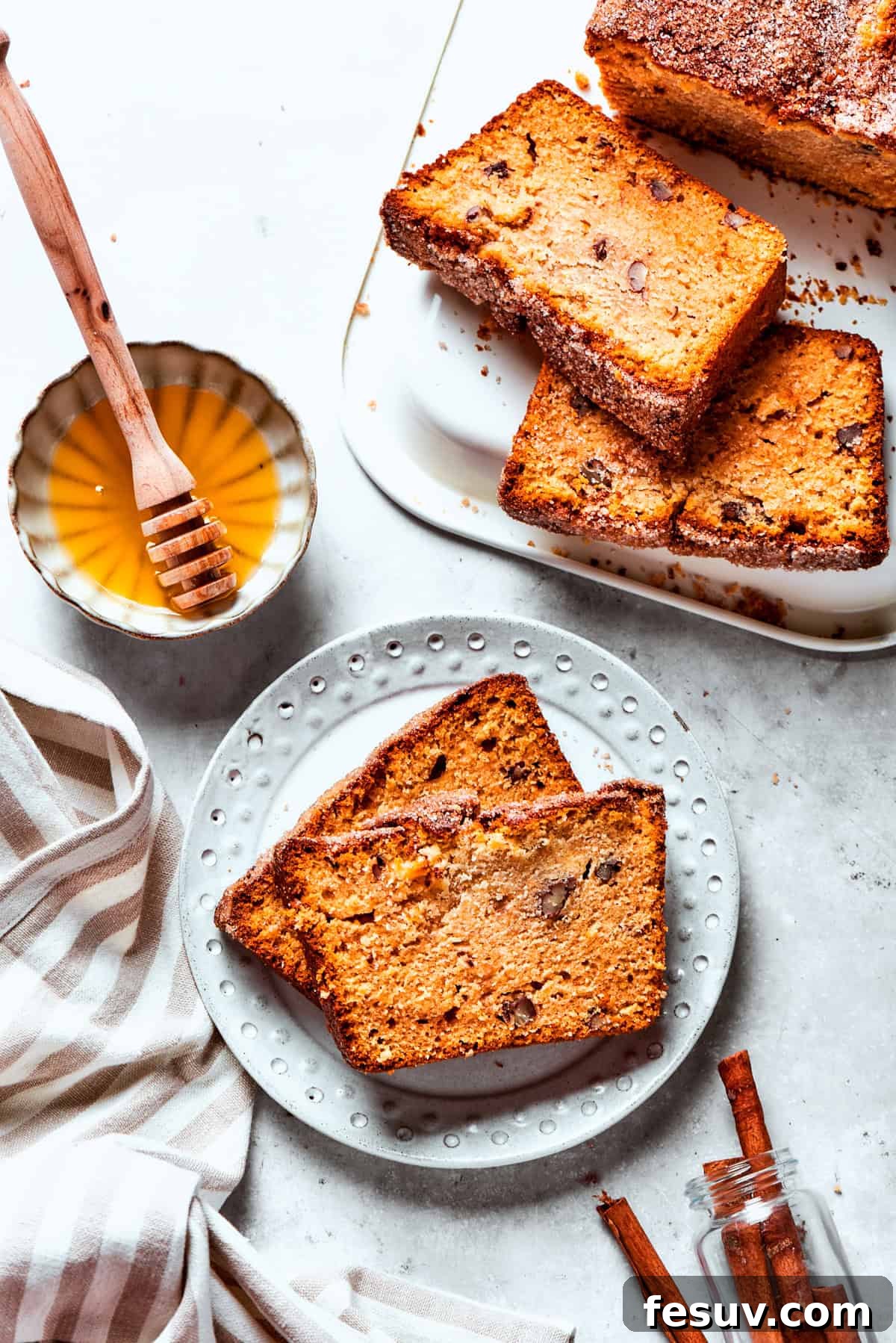 Two generous slices of Amish bread are served on a plate, with a bowl of honey and more bread set invitingly nearby.