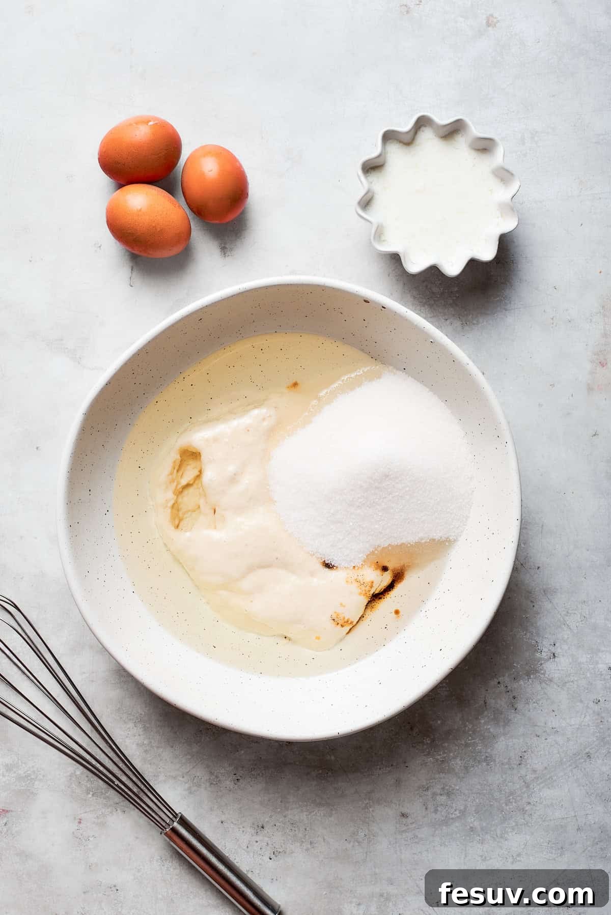 Granulated sugar is added to the wet ingredients in a bowl for Amish friendship bread batter.
