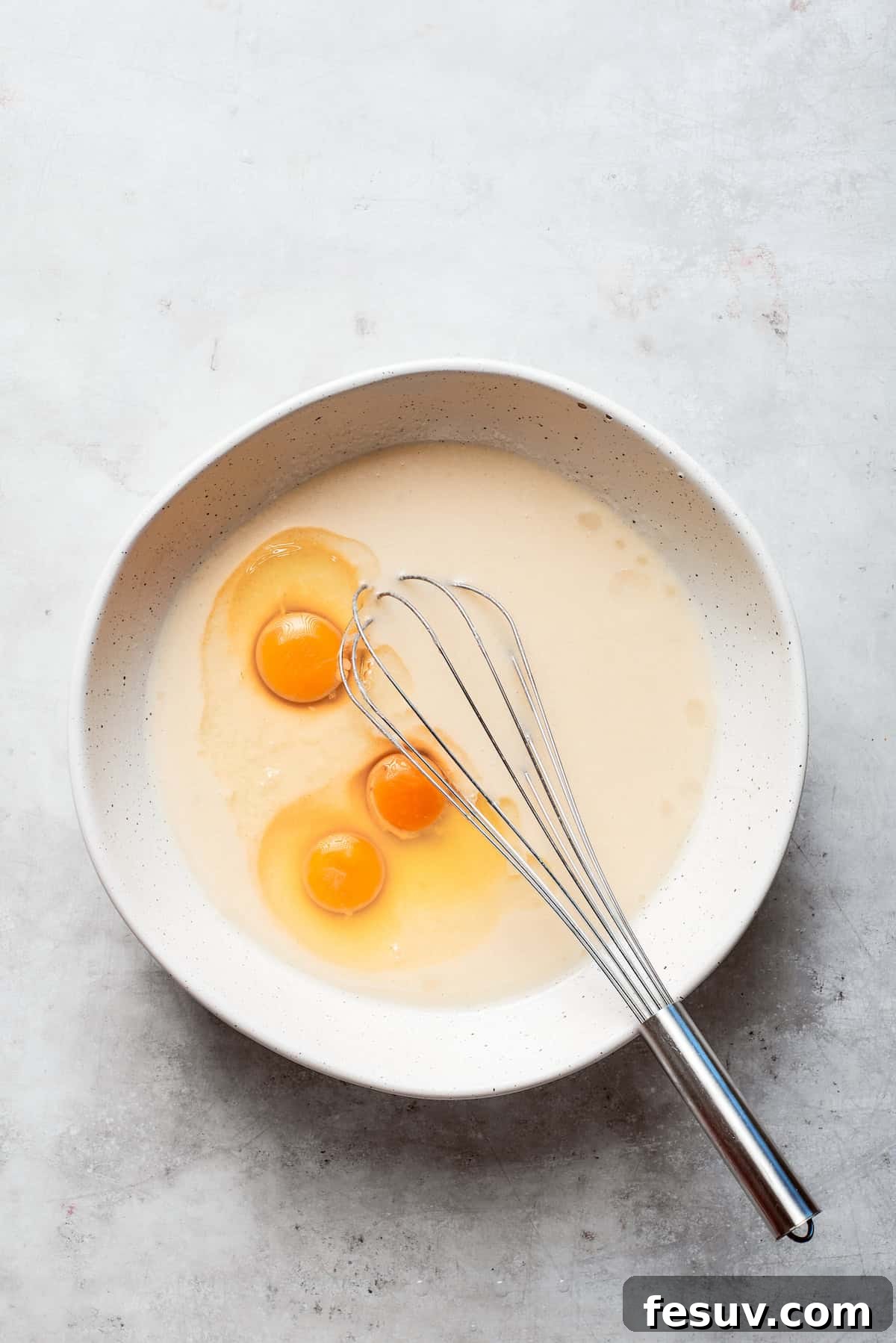 Large eggs are carefully cracked and added to the batter of Amish friendship bread.