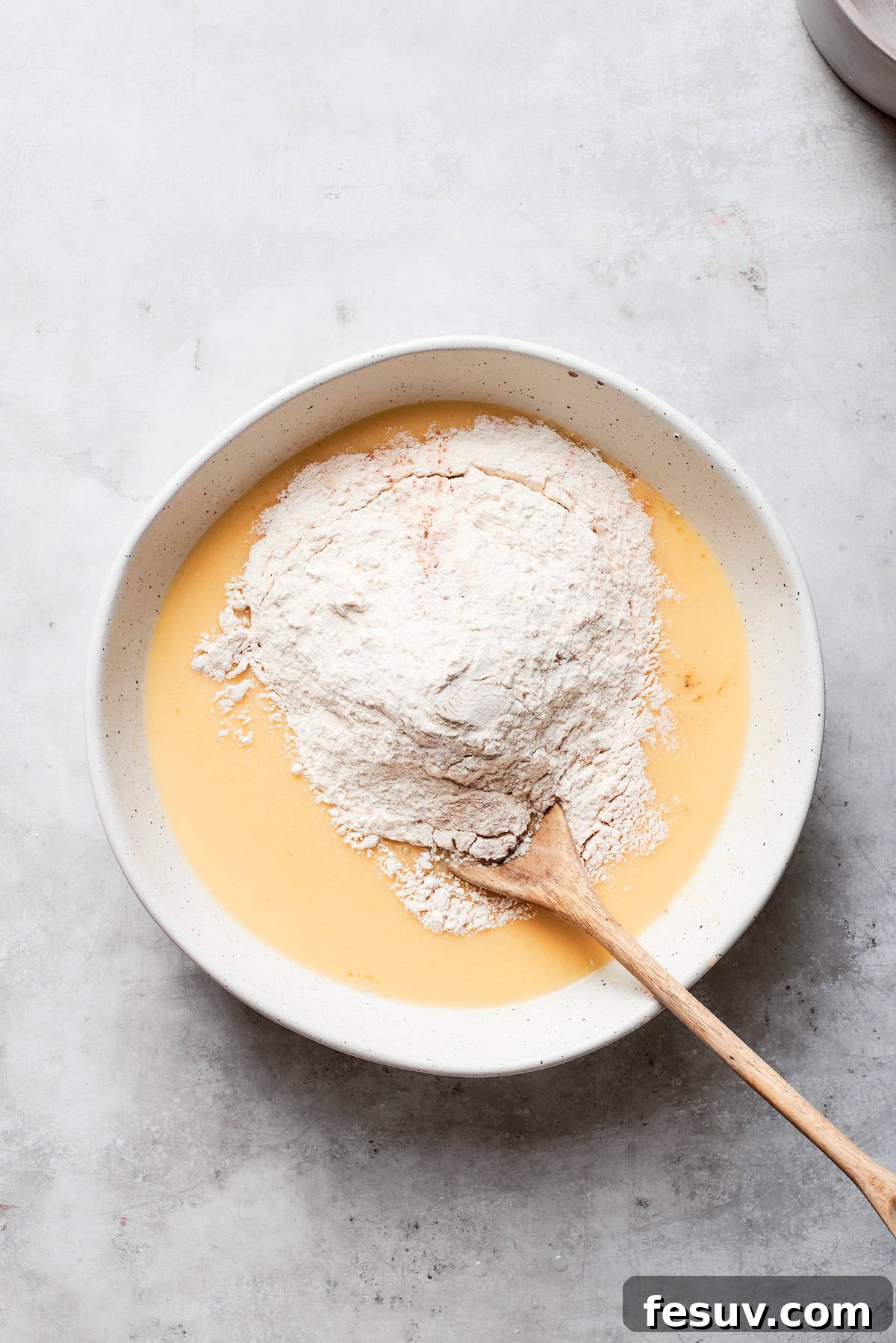 All-purpose flour is gradually stirred into the wet batter, thickening the mixture.