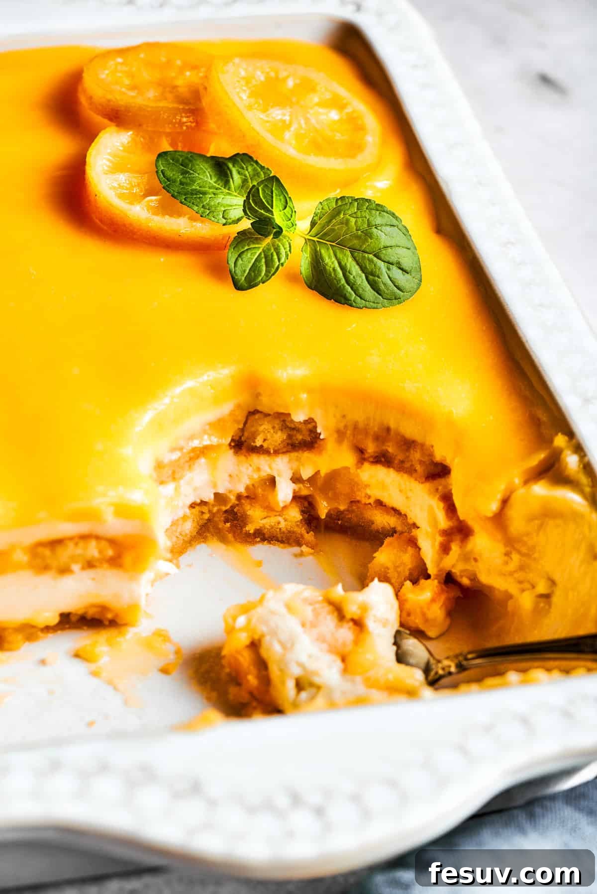 Sun-Kissed Lemon Tiramisu 20 A baking pan filled with delicious lemon tiramisu, with several slices already cut out, ready to be served.